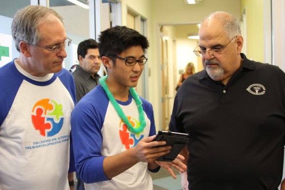 Jared Izumi, CES school psychology student, shows an app he created to Joe Donnelly, M.D. (at left), director of the Center for Autism, and Don Cardinal, Ph.D., incoming director. The app will help families keep connected with autism programs in their local schools.