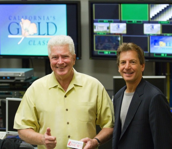 two men smiling in front of tvs