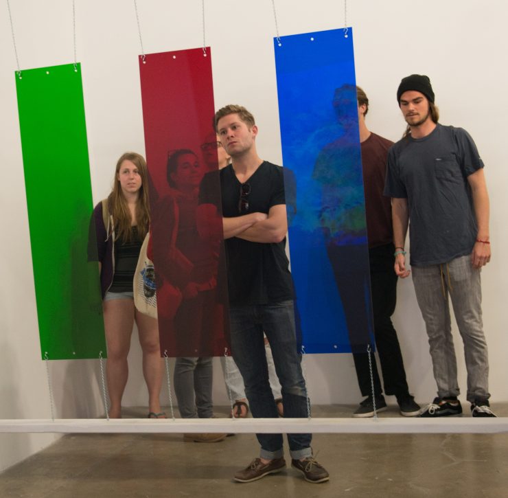 Chapman student examines an installation art piece that employs colored panels to influence video projections.