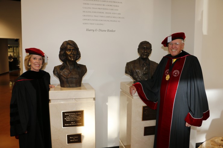 man and woman smiling next to busts