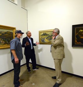 three men talking in art museum