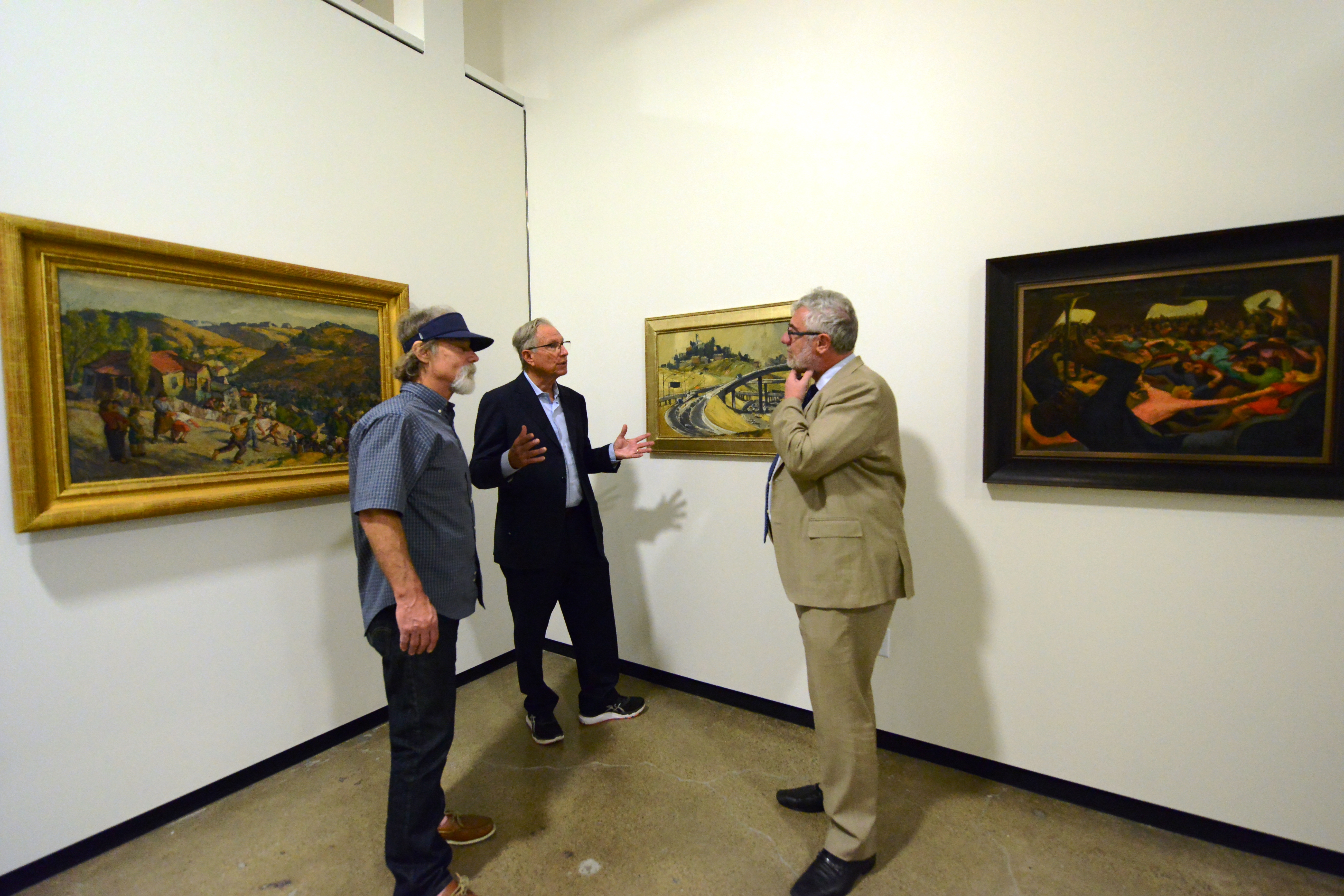 three men talking in art museum