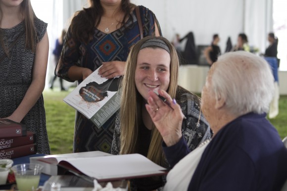 Holocaust survivor signing a book for a woman