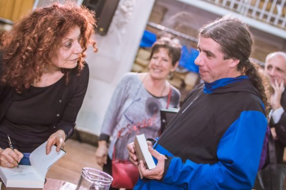 woman signing book and listening to man