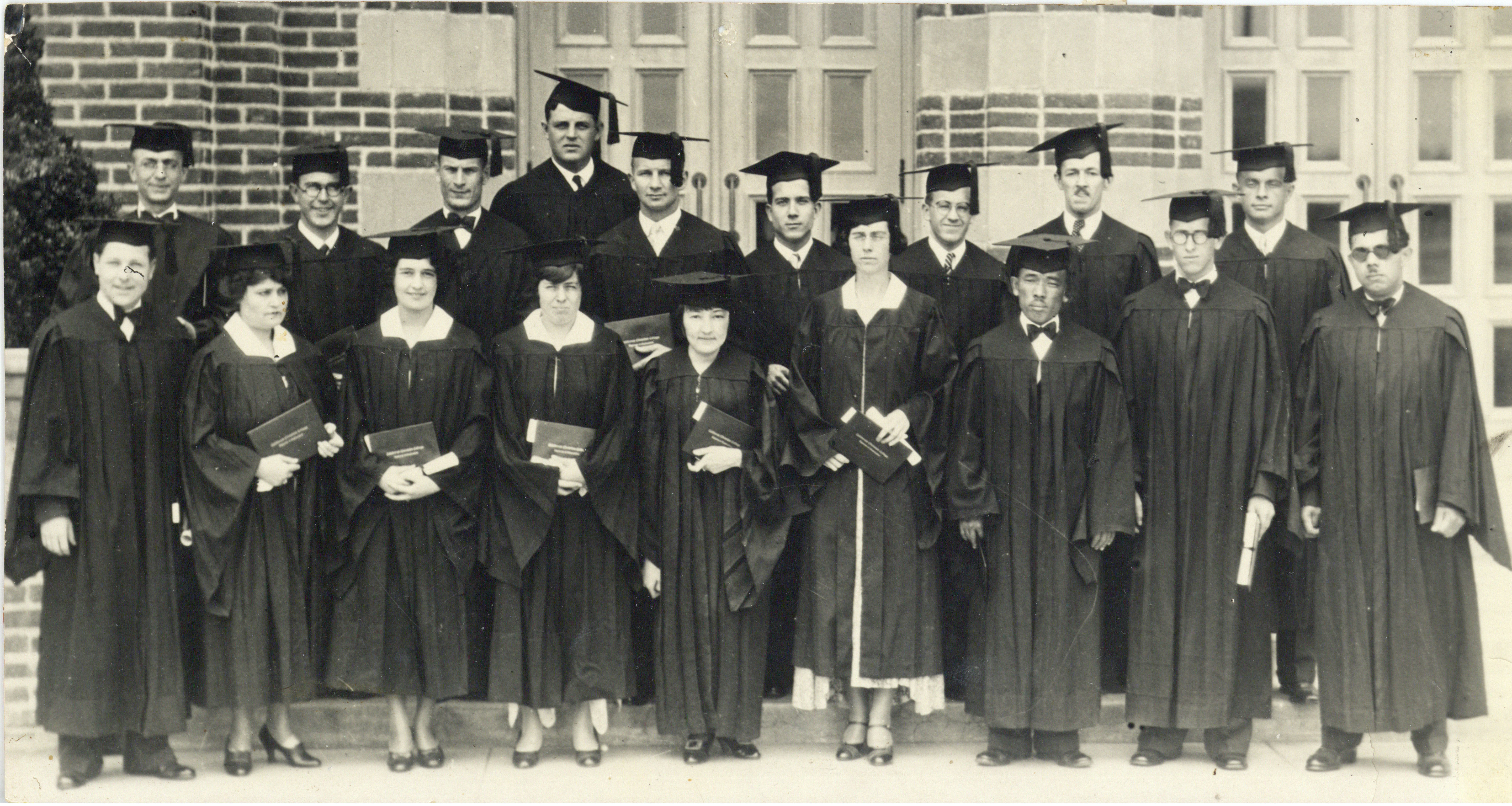 graduating class standing with diplomas