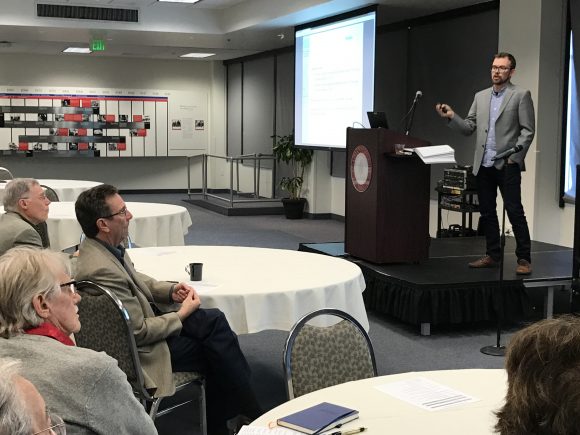 Vernon Smith (lower left) watches and listens to a presentation by Erik Kimbrough, his former student, now of Simon Fraser University, at the January 4 conference honoring Smith's 90th birthday.