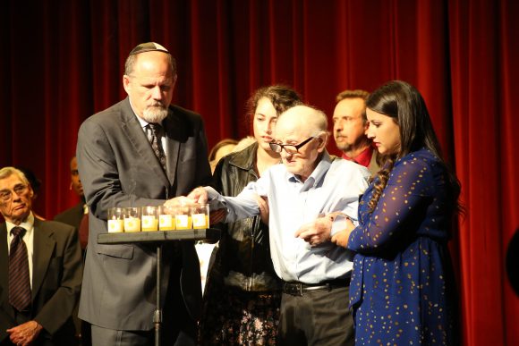 group of people lighting a row of 6 candles