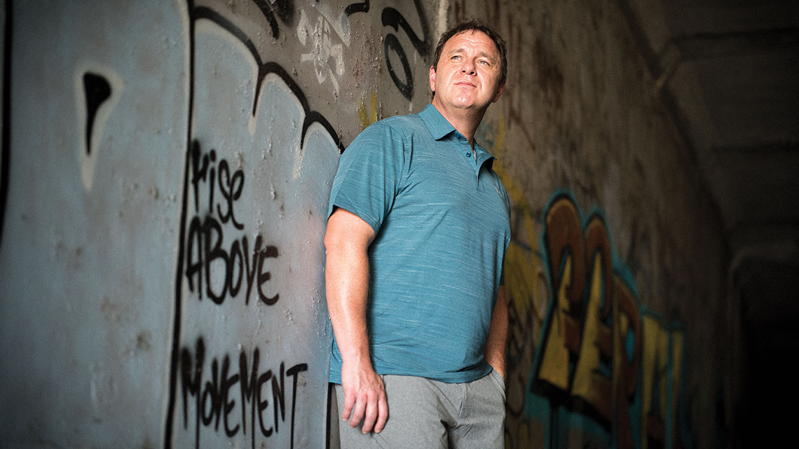Peter Simi standing in front of graffiti wall
