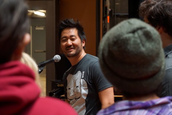 Kishi Bashi at microphone smiling at students