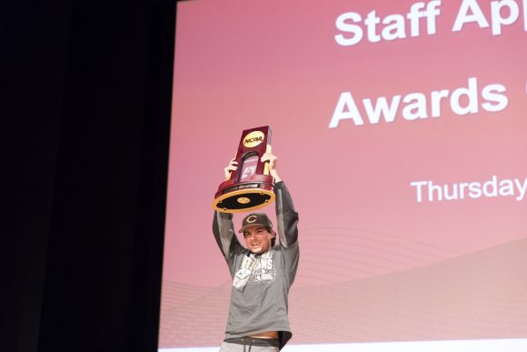 baseball player holds up trophy.