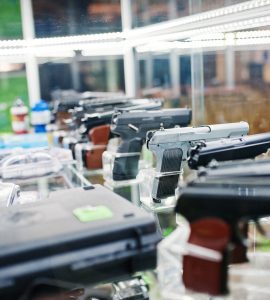 Different guns and revolvers on shelves store weapons on shop center.