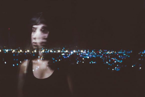 Photograph of blurred girl in front of border at night.