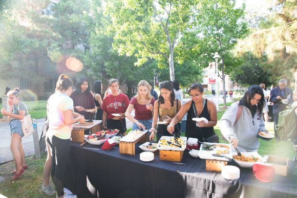 Students take food from an outside table. 