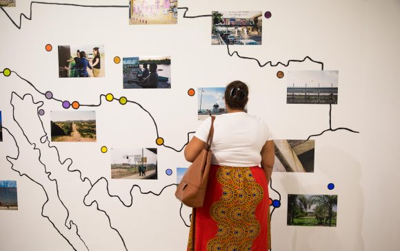 A woman in front of an artwork resembling a map.