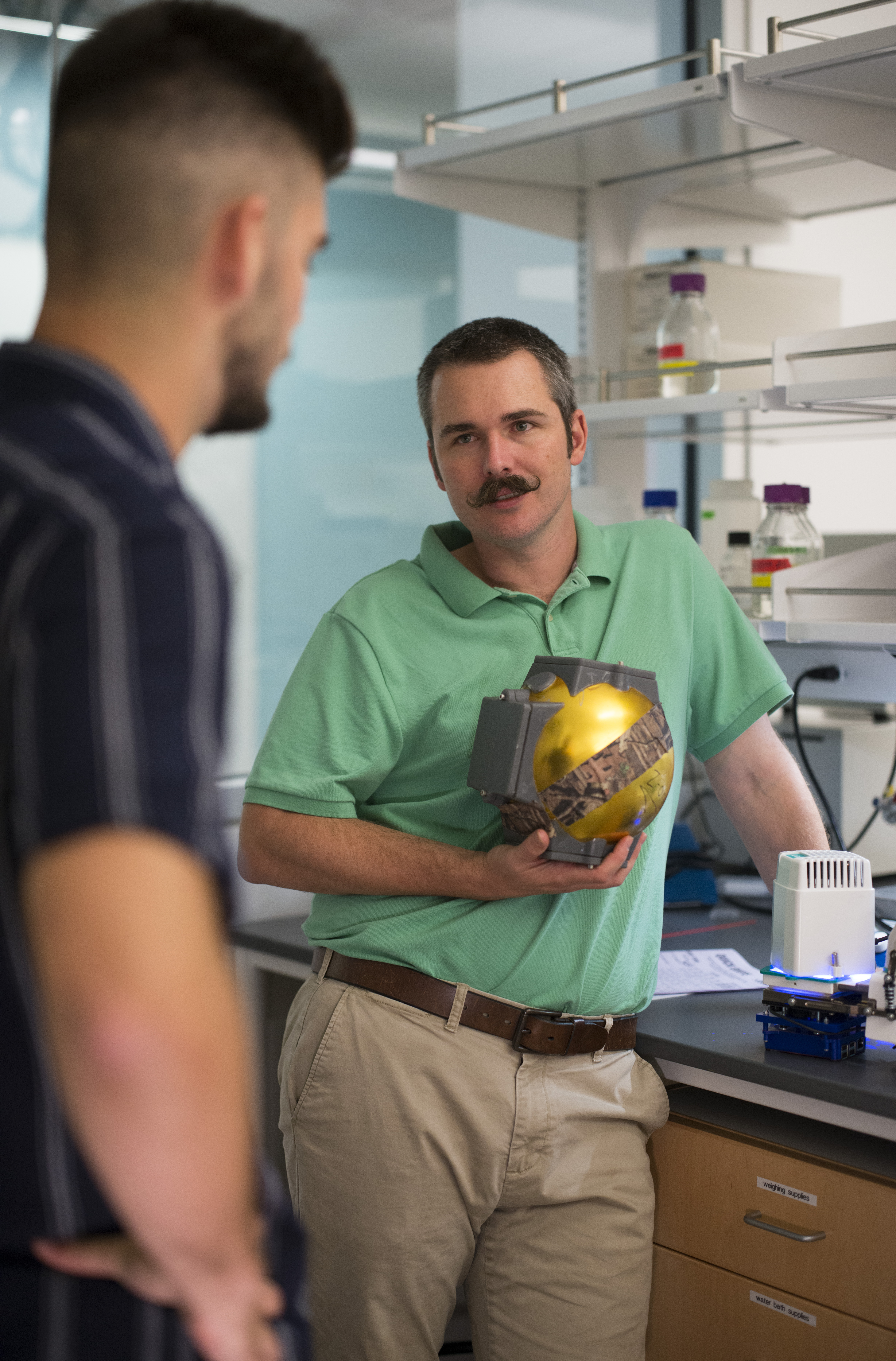 Biological sciences student Alex Drives '21, left, talks with Carter Berry, Ph.D, about equipment Drivas helped design to advance Berry's plant research. Photo by Dennis Arp.
