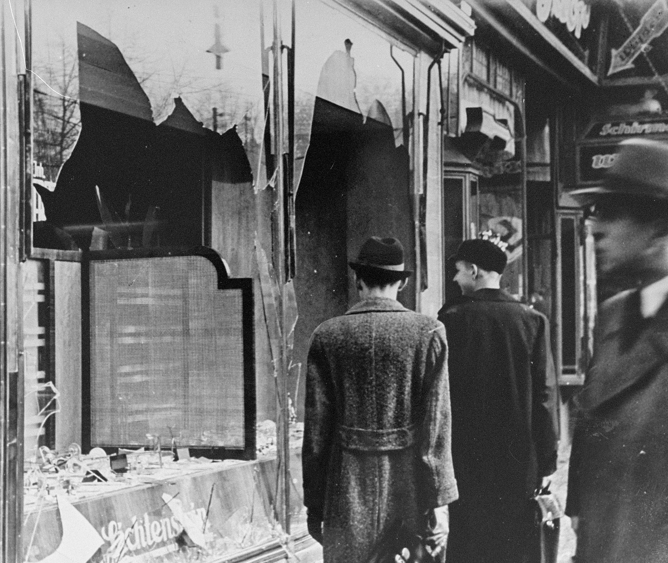 Men in hats walk past broken windows