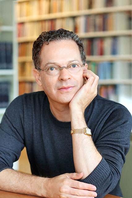 Man in front of books, seated