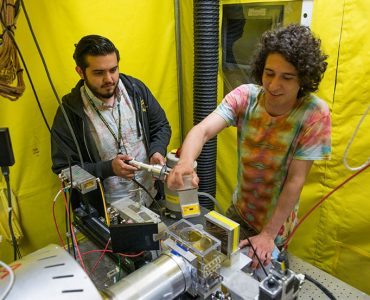 Researchers standing over electronic device