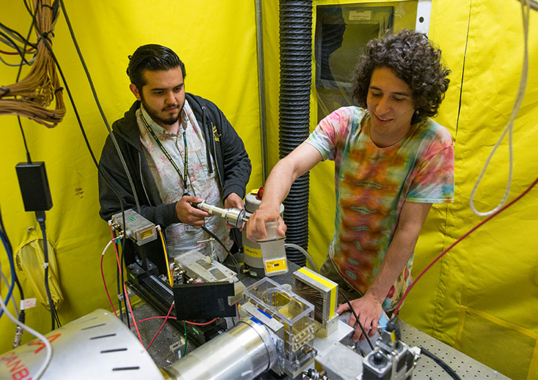 Researchers standing over electronic device