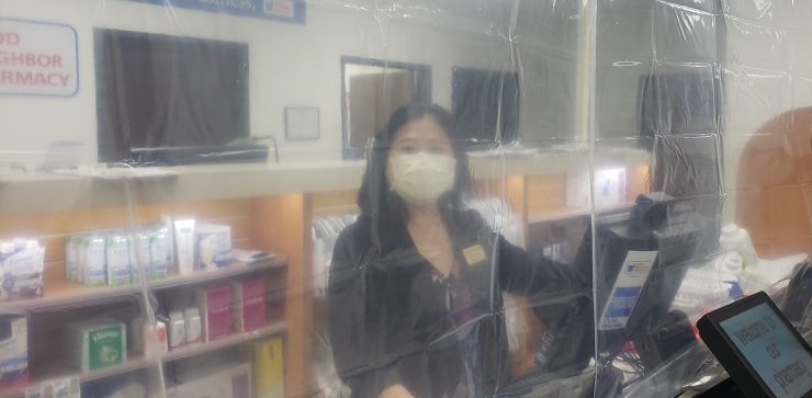 pharmacist behind plastic barrier