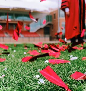 confetti on field with person in academic robes in background