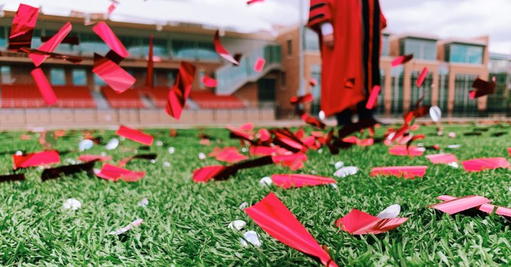 confetti on field with person in academic robes in background
