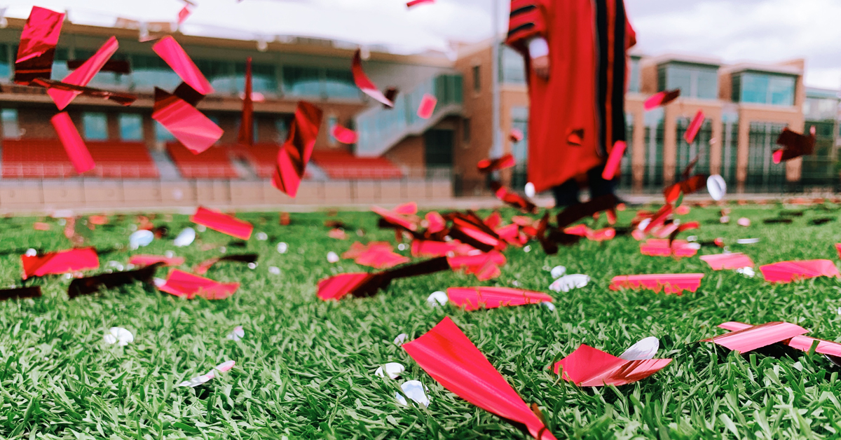 confetti on field with person in academic robes in background