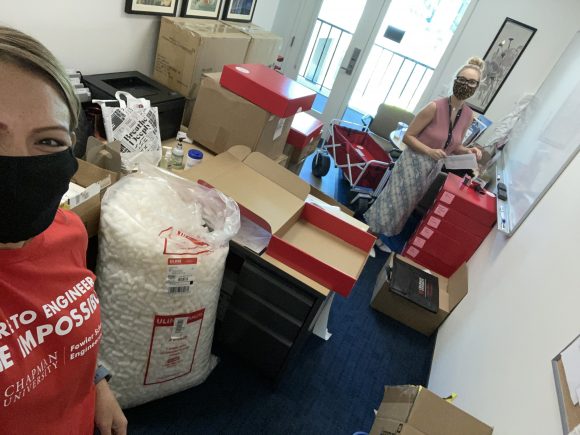 Boxes containing laptops and supplies for new students at Chapman’s Fowler School of Engineering are prepped for shipping by two university staff members.