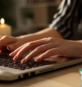 Person typing on laptop on power outage with candles.