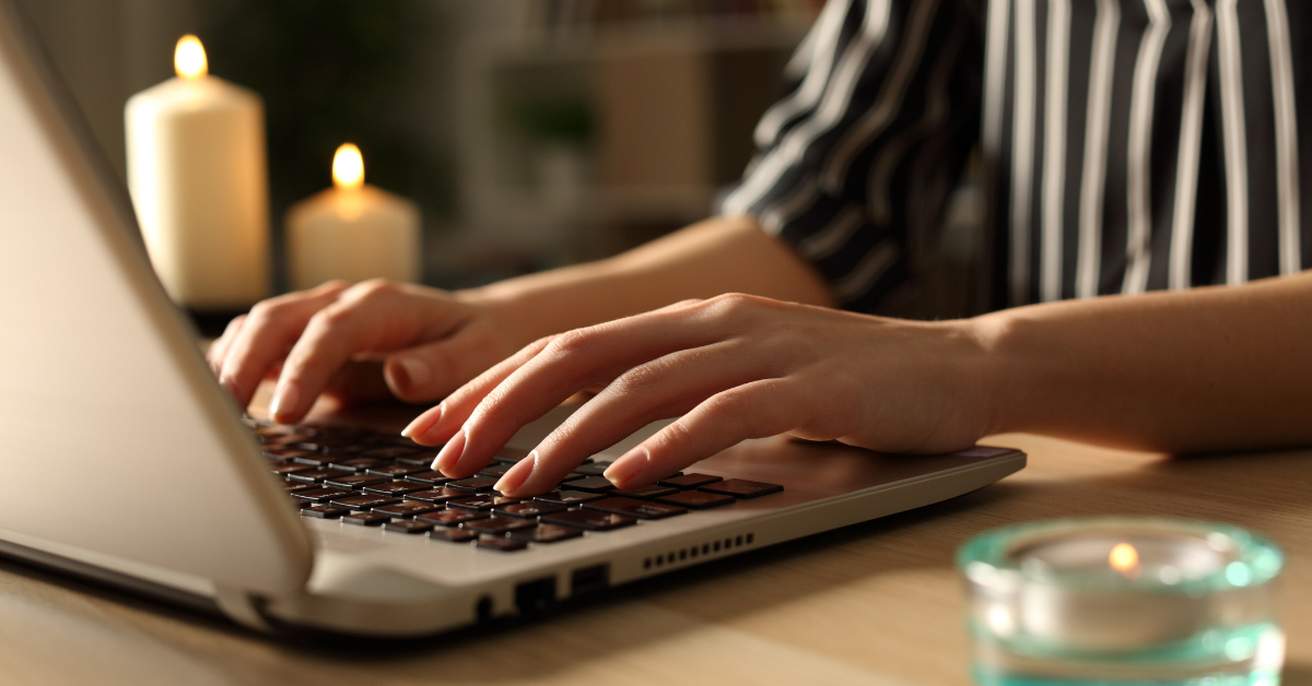 Person typing on laptop on power outage with candles.