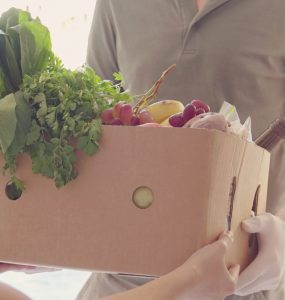 Person handing another person a box of produce.