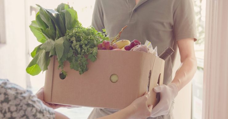 Person handing another person a box of produce.