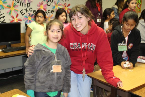 A Chapman student standing with a student from Higher Ground in a classroom.