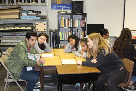 Chapman students seated at a table and reading to students from the community.