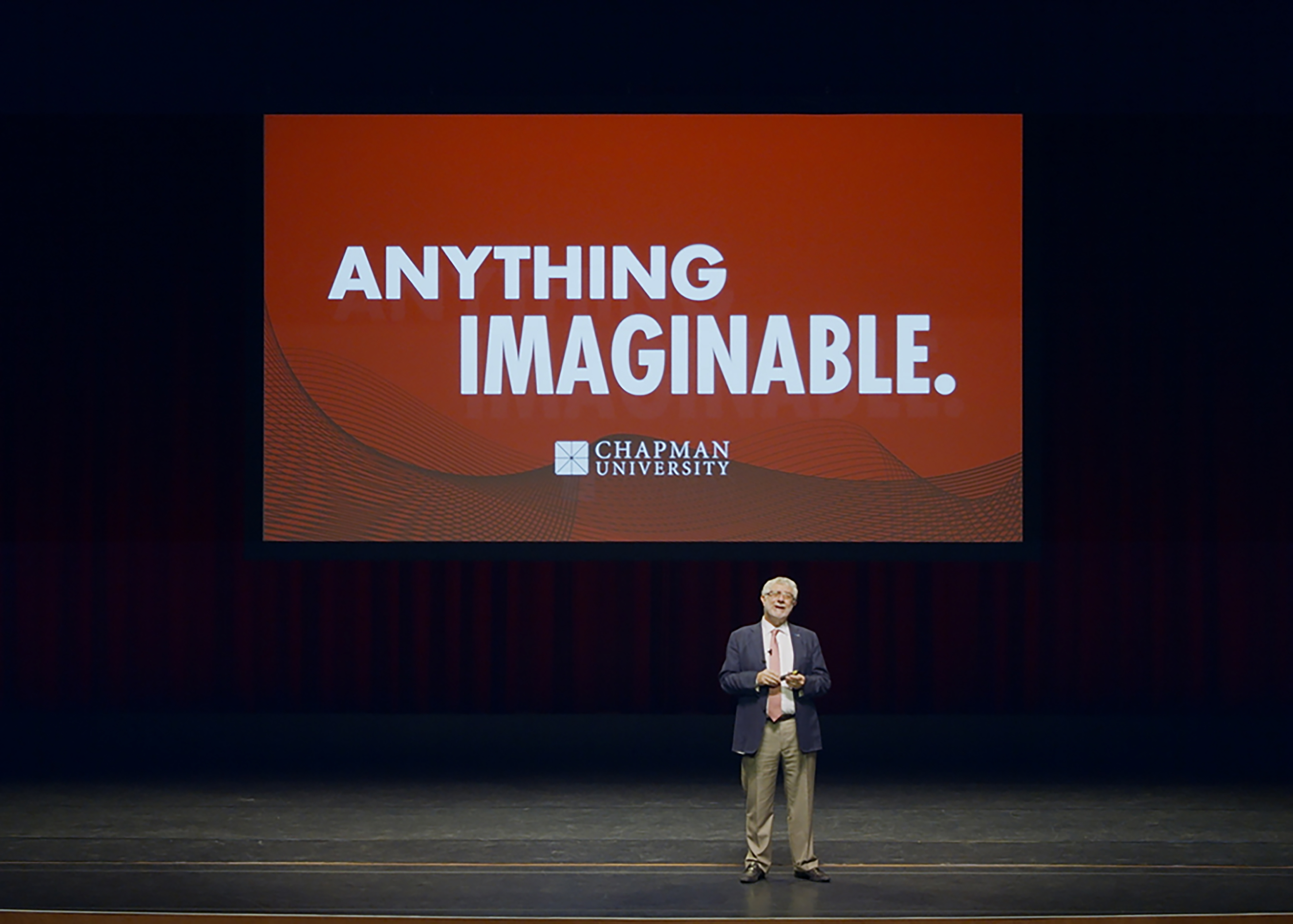 President Daniele Struppa on stage before a screen that reads Anything Imaginable