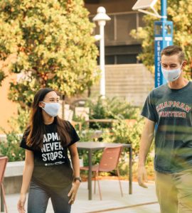 Two chapman students in face masks walking through campus.