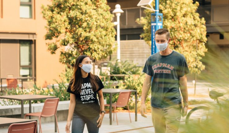 Two chapman students in face masks walking through campus.