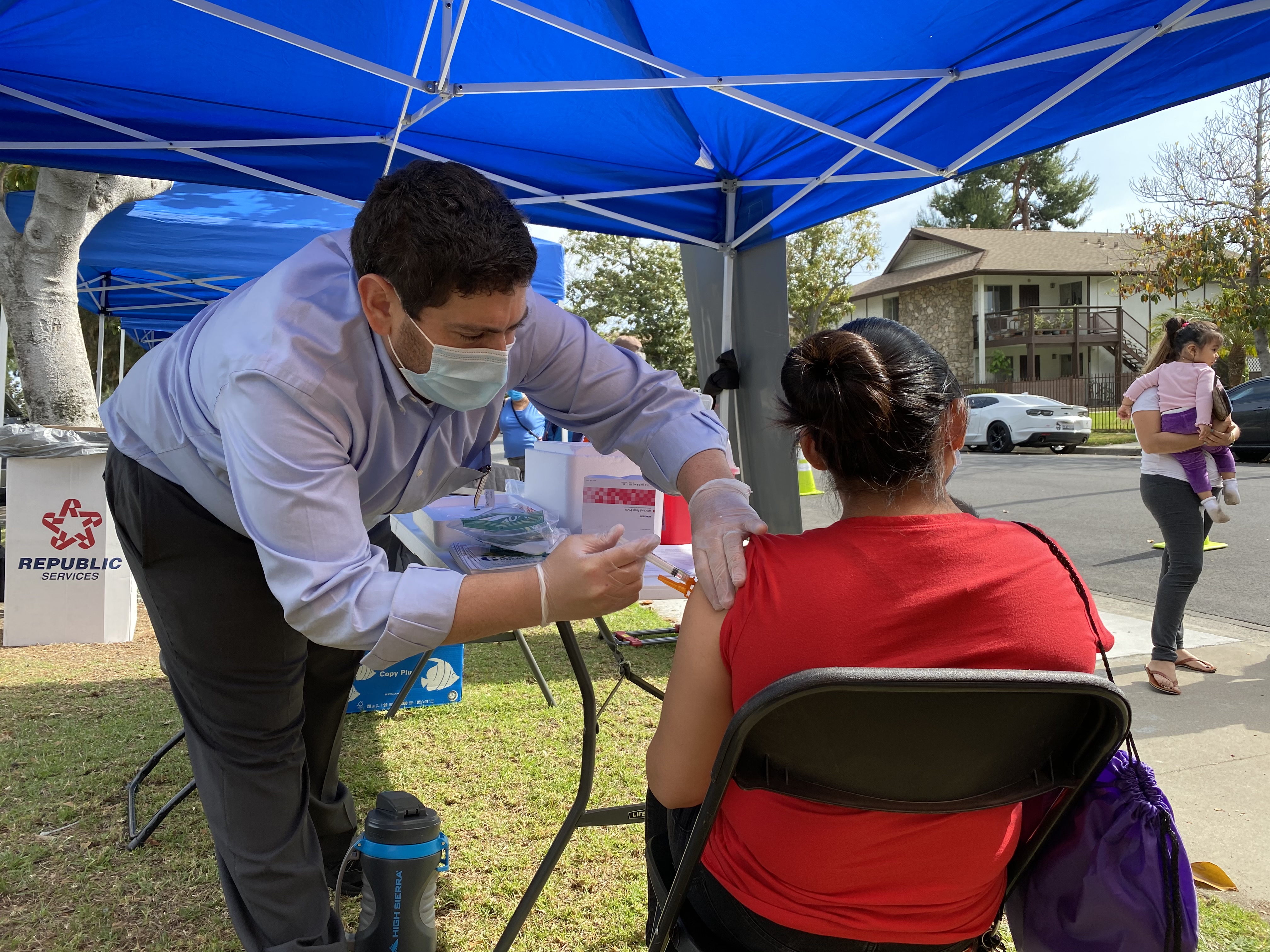 Medical personel gives a COVID-19 vaccination to an anonymous woman in an outdoor booth.