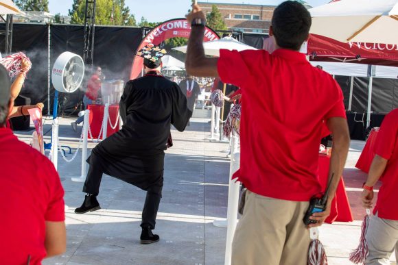 rear view of male graduate taking a jaunty step