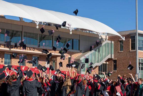 group of grads throwing their mortar board caps in the air