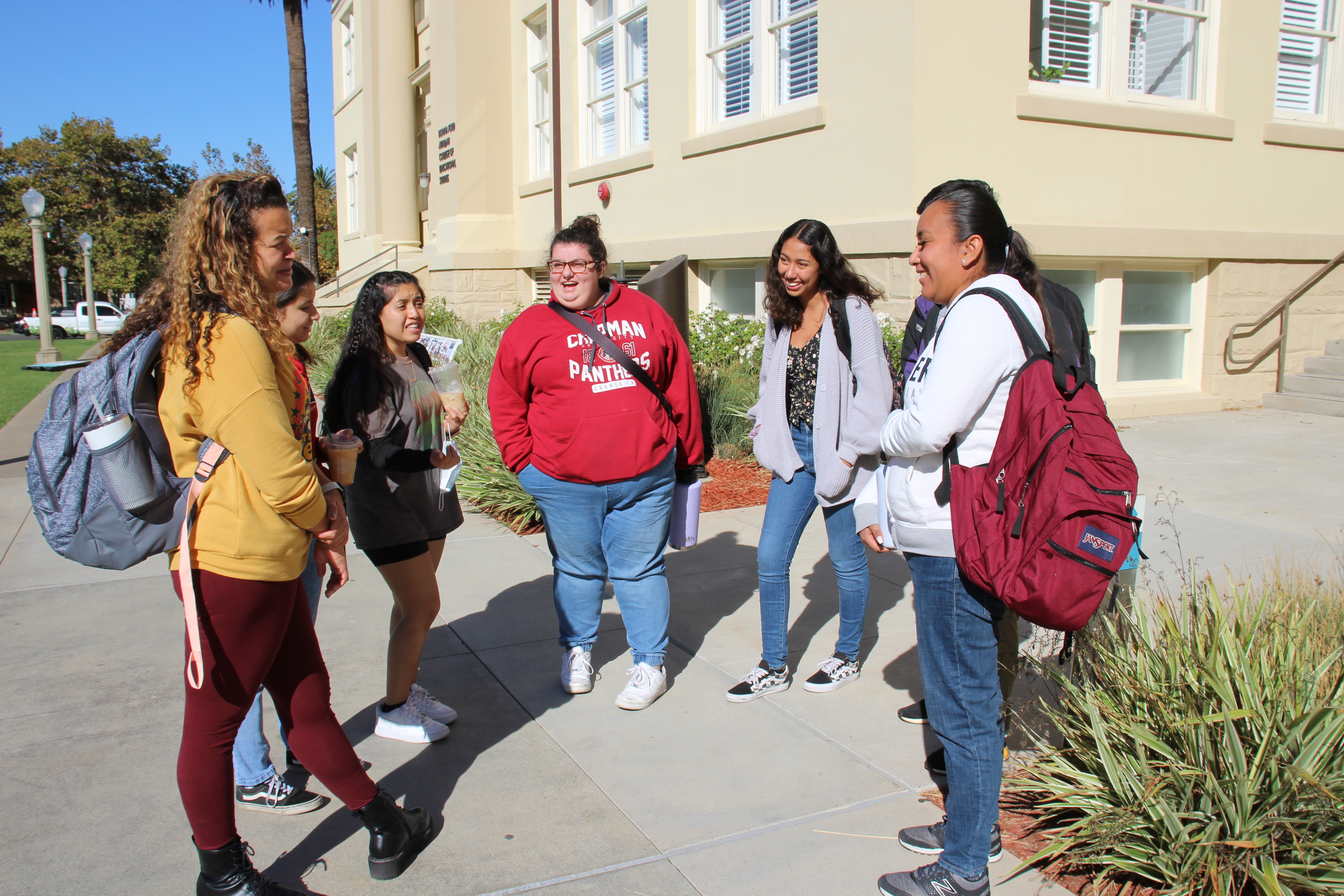 Angalina Maldonado, left, and Aidee Guerrero, right, gather with fellow C-TAG students after class in front of Chapman’s Reeves Hall.