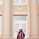 camila correa in graduation robes in front of memorial hall