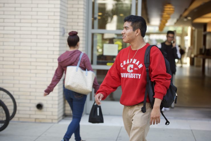 male student in chapman sweatshirt leaving building