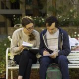 woman and man sitting on bench at college studying