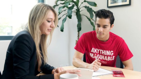 woman and man sitting at a table looking at a calculator