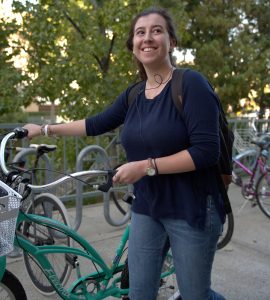 young woman walking bike and smiling
