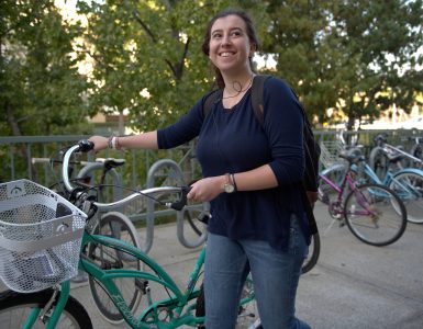 young woman walking bike and smiling