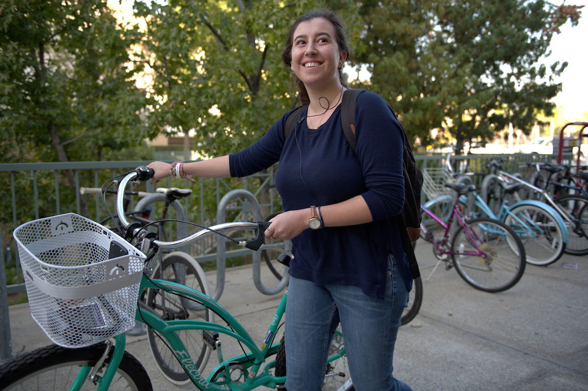 young woman walking bike and smiling