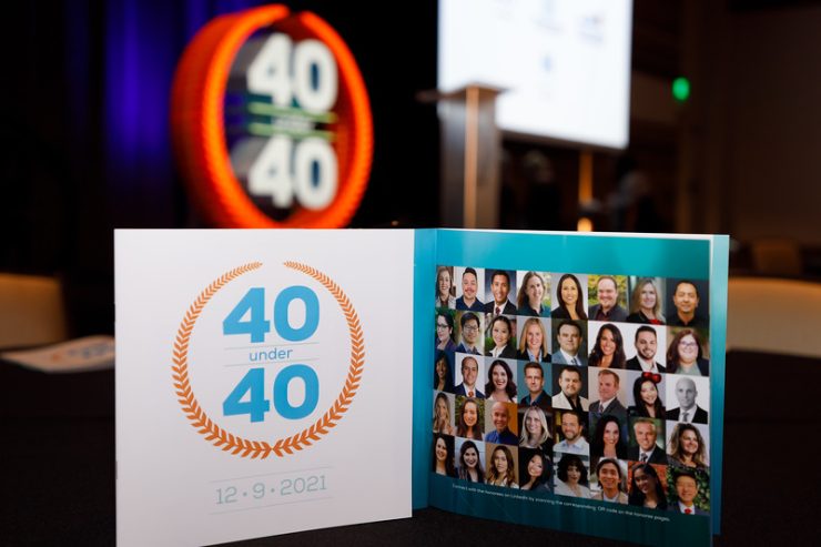 A photo collage of the 40 Under 40 recipients is displayed on stage.