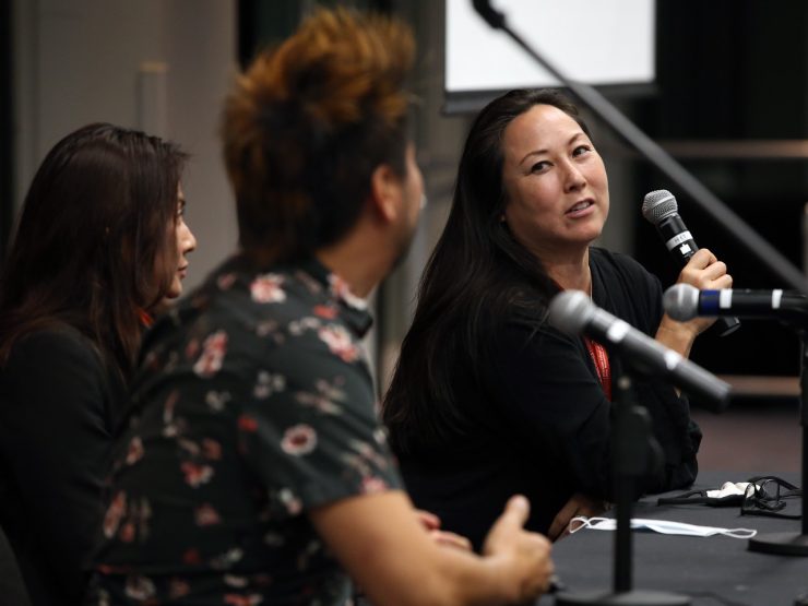 Professor and guest speaker seated at conference table with microphone.